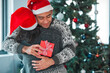 Couple, hug and giving a present on Christmas in home with love and care on vacation or holiday, Happy, man and thank you for package or box with ribbon and giveaway celebration of Xmas with gift