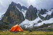 Orange tent with mountains on the background in cloudy day