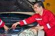Senoir asian technician man in red formal suit and team checking car battary and engine in car garage service.