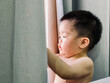 © dmnapat - Close of asian baby boy looking at curtain through window  without clothes at home, view from side