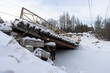 View of the collapsed road bridge. Collapsed bridge over a small river. Fallen damaged bridge. Consequences of an emergency. Cold winter weather. A lot of snow.