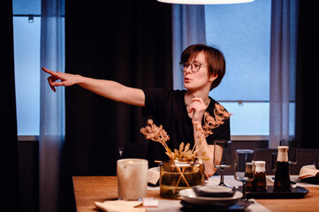 This striking image captures a young adult gesturing actively at a dinner table, potentially giving instructions or sharing a story. 