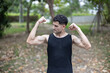 A Man flexing his bicep showing his strong muscle in a park