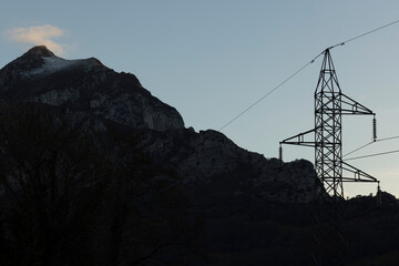 Wall Mural - Electrical tower with wires next to high mountain peak with fog