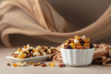Wall Mural - The mix of various nuts and raisins in a white bowl on a beige background.