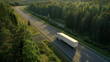 A truck drives along a forest-lined road in the tranquility of dawn.
