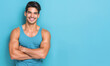 A man with a blue tank top is smiling and posing for a picture
