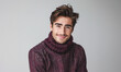 A man wearing a purple sweater and scarf is smiling