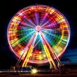 Vibrant Rainbow Ferris Wheel Spinning at Night in the Amusement Park