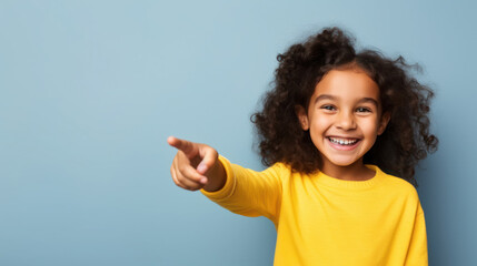 Canvas Print - cheerful smiling child points with finger, bright background, copy space