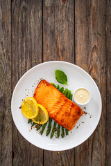 Poster - Fried salmon steak with cooked green asparagus and mayonnaise served on wooden table

