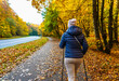 Autumnal Nordic walking - mid-adult beautiful woman exercising in city park using  Nordic walking poles

