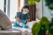 Chambermaid wearing protective face mask and gloves while working at a hotel room Chambermaid wearing protective face mask and gloves as precaution against coronavirus while working at a hotel