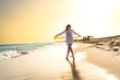 Beautiful woman holding shawl walking on sunny beach
