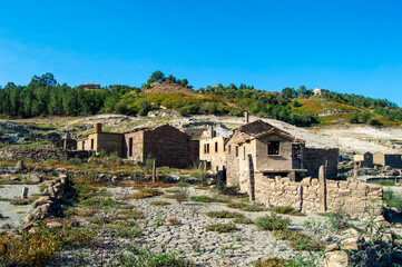 Poster - a dirt and stone building on a hill side with a forest in the background