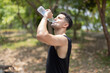 A man drink water from bottle in a park