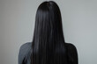Rear View of Woman with Long Black Hair and Hairpin against Grey Background