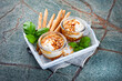 Traditional Greek honey pot served with goats cheese, pine nuts and grissini as close-up in a rustic rustic wooden tray
