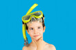 Child with mask tuba with hand on chin thinking about question,thoughtful expression.Concept of doubt and looking aside. Snorkeling,swimming,vacation concept on blue background.Caucasian male model