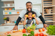 © chokniti - Happy African American Family at Home: Mother and Father Hug Their Young Daughter and Son, Sharing Love and Fun Together, Portraying Cheerful Moments of a Black American Household
