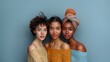 © Jay Koppelman - Studio portrait of three diverse women in colorful ethnic attire posing against a plain blue background
