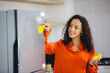 African female putting sticky note on refrigerator to remind her important job, work, plan, reminder, task and goal. Attractive smart Latin women putting or reading her note house activity checklist.
