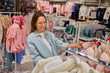 Enthusiastic curious pregnant woman doing shopping at newborns store department