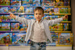 Delighted little boy child standing with toys showcases behind back