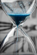 Blue sand hourglass on analog clock background