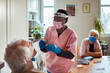 © Marko Geber - Home healthcare worker doing covid swab test to elderly man with wife watching