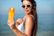 Beautiful woman applying cream sunscreen on a tanned face. Sunscreen. Skin and body care. The girl uses a sunscreen for her skin. Portrait of a female holding suntan lotion and moisturizing sunscreen.