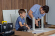 Father and son assemble new furniture on floor of new apartment, concept of experience and training.