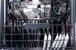 An open dishwasher is filled with clean dishes in kitchen