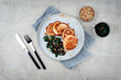 Traditional American pancakes with spinach, pine-nuts and raisins served as top view on a Nordic design plate with cutlery
