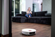 Robot vacuum cleaner cleans a room while a woman is on the phone