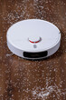 Modern robotic vacuum cleaner removing scattered rice from floor, top view
