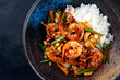 Traditional Thai fried king prawns with vegetable, cashew nuts and rice served as top view in a design bowl with text space left