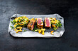 Traditional Japanese gourmet tuna fish steak tataki with tropical fruit tartar and cashew nuts served as close-up on a Nordic design tray with copy space