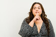 Quiet gesture: plus-size woman with finger on lips in a studio setting with copy space