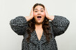 Joyful plus-size woman with a surprised expression in a trendy blouse posing in a studio