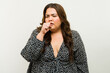 Studio portrait of a curvy woman coughing against a simple backdrop