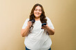 Joyful plus-size woman holding a smartphones and a credit card and buying some stuff online