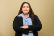 Confident plus-size businesswoman in a suit, posing with arms crossed against a neutral background