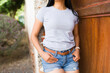 Closeup of casual young hispanic woman posing in a plain grey t-shirt against a rustic backdrop, perfect for mockups