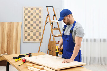 Canvas Print - Young worker using electric drill at table in workshop