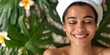 Relaxed smiling woman with a spa headband receiving a facial treatment surrounded by greenery