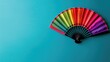 © Tati - Colorful hand fan open against blue background
