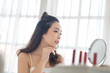 Attractive Asian Female model in white vest looking at makeup mirror at room. Skin care, Beauty face, Hairstyle.