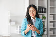 © Natee Meepian - Business woman using mobile phone at a company is typing a conversation on the internet