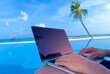 Nomad digital with laptop and running remotely with bright scenic view near poolside on the beach in summer time